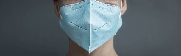 Person wearing surgical mask isolated on a gray background - Photo, Image