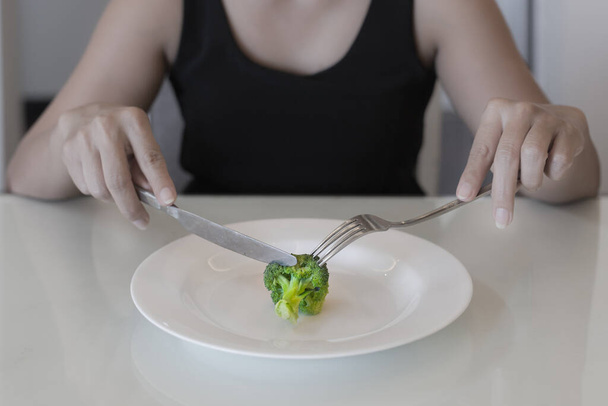 Kobieta jedząca małą porcję warzyw. Dieta niskokaloryczna. - Zdjęcie, obraz