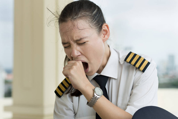 Profesionální kapitán pilot vyčerpaný z dlouhých hodin letu, sedí na letišti a čeká na zpožděný let. - Fotografie, Obrázek