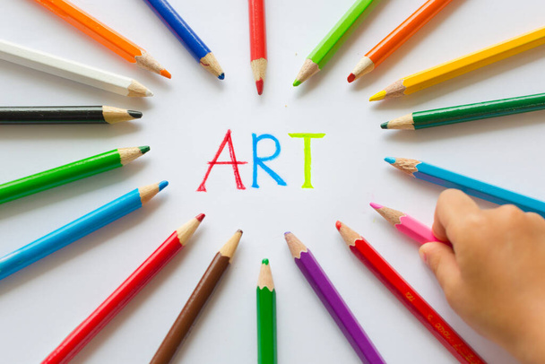 Egy gyerek színes ceruzákat terít, szívformát csinál, középen a "művészet" szóval. Művészeti oktatási vektor koncepció az osztályteremben. - Fotó, kép