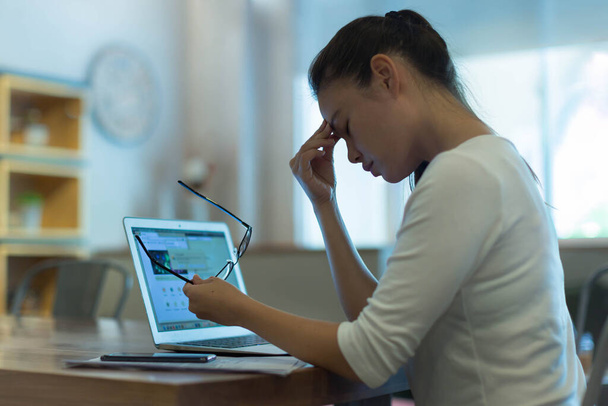 Wyczerpana i zestresowana kobieta, robiąca sobie przerwę od komputera, pocierająca obolałe oczy. - Zdjęcie, obraz