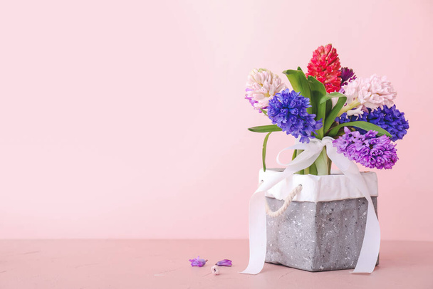 Doos met mooie hyacint bloemen op tafel tegen kleur achtergrond - Foto, afbeelding