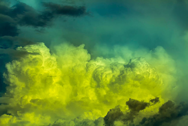 bewolkte hemel met gele rook bewolkt en groen licht - Foto, afbeelding