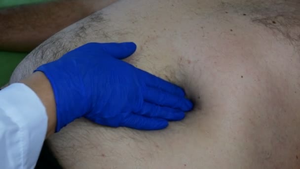 Medico palpa con mano in gomma blu guanto stomaco di uomo malato che si trova a letto. Primo piano
. - Filmati, video