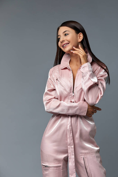schöne Mädchen Modellierung mit Mode rosa Overall Kleid und Kleidung tragen weiße High Heels, grauen Hintergrund. Modekonzept, Kopierraum. - Foto, Bild