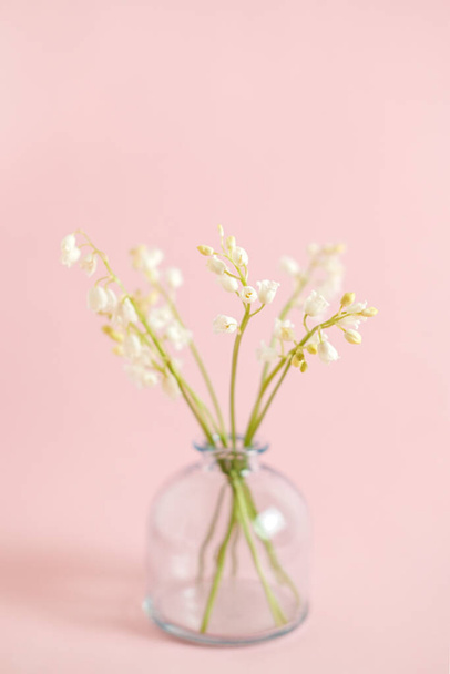 Greeting card with white lily of the valley on pink background for celebration Mothers Day, wedding, March 8. Nature concept. Home garden in vase. Summer green floral design. Selective focus. - Zdjęcie, obraz
