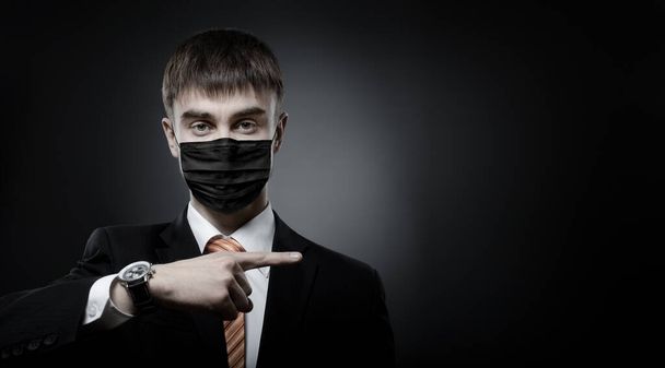 concept coronavirus epidemic, portrait businessman in black medical mask on face and black costume  - 写真・画像