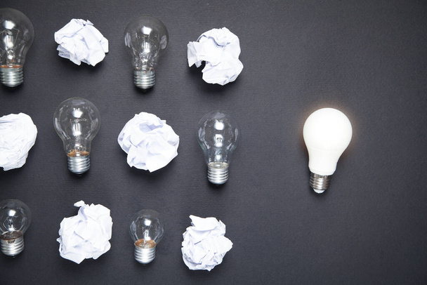 Light bulb and crumpled papers in the black background. Idea - 写真・画像