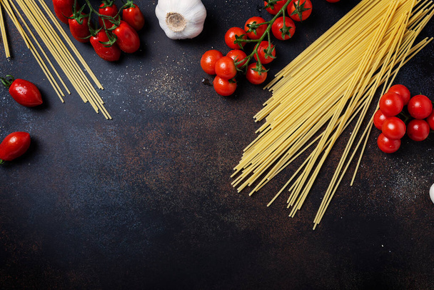 イタリアのパスタを調理するための成分:スパゲティ,黒テーブルの上にトマトとニンニク.コピースペース付きのトップビュー画像 - 写真・画像