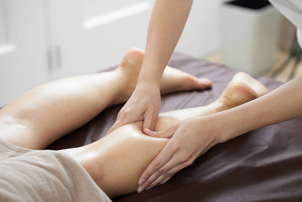 Uma mulher recebe uma massagem nos pés em um salão de beleza iluminado
 - Foto, Imagem