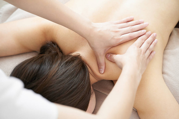 Japon bir kadın açık estetik bir salonda omuz masajı yaptırıyor. - Fotoğraf, Görsel
