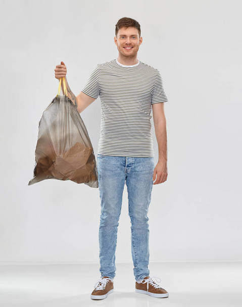 smiling man holding trash bag with paper waste - Foto, afbeelding