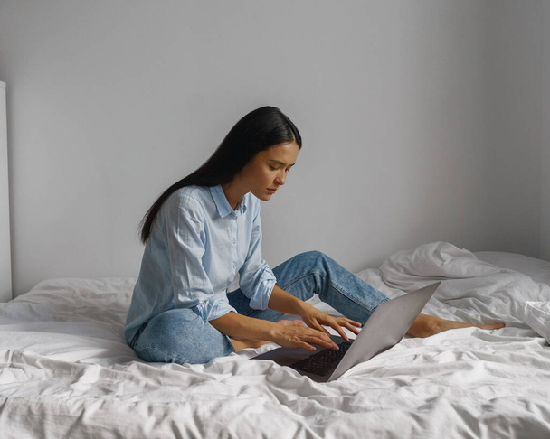 молода жінка працює вдома на ноутбуці в ліжку #LockdownArt
 - Фото, зображення