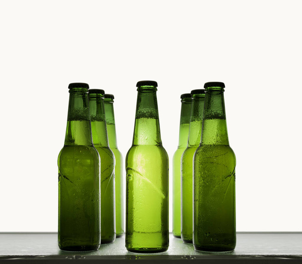 Bouteilles de bière vertes refroidies dans des gouttes d'eau sur une étagère sur un fond clair
. - Photo, image