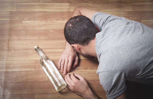 Caucásico alcohólico hombre con vodka acostado en el suelo
. - Foto, imagen