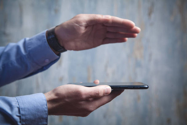 Mann hält Smartphone mit schützender Geste Technologiekonzept - Foto, Bild