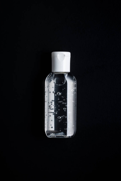 Antibacterial cleaning gel. Coronavirus prevention. Hand sanitizer gel on black background. - Φωτογραφία, εικόνα