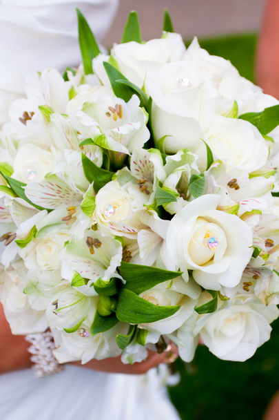Наречена тримає свій букет квітів на весільній церемонії, вдягнувши білу сукню
 - Фото, зображення