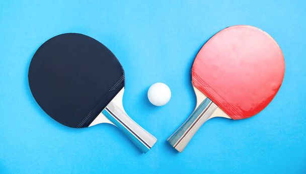 テーブルテニスラケットと青い背景の白いプラスチックボール. - 写真・画像