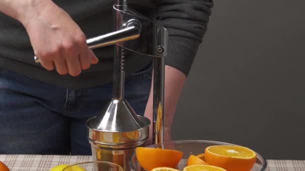 Exprimir una fruta naranja con una prensa manual, cerrar la vista, hacer un vaso de fresco. Naranjas frescas sobre una mesa de madera, enteras y cortadas en rodajas
. - Metraje, vídeo