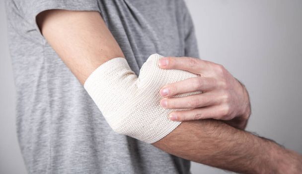 Man hand with elastic bandage on elbow. - Fotó, kép