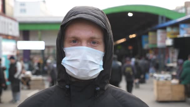 Ritratto di giovane uomo con maschera medica si trova in strada. Il tizio che indossa una maschera protettiva dal virus all'aperto tra la gente affollata. Concetto di salute e sicurezza vita da pandemia di coronavirus - Filmati, video