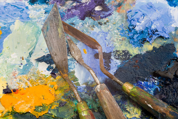 Cuchillos de paleta de artistas bien utilizados en una paleta de pintura multicolor
 - Foto, imagen