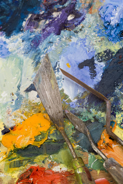 Cuchillos de paleta de artistas bien utilizados en una paleta de pintura multicolor
 - Foto, imagen