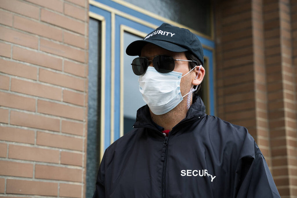 Security Guard Standing In Face Mask At Entrance - Foto, Imagen