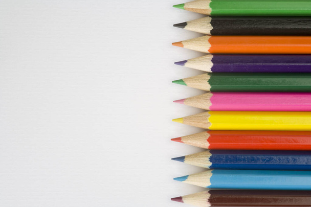 Childrens colouring pencils on a plain white textured paper background - Photo, Image