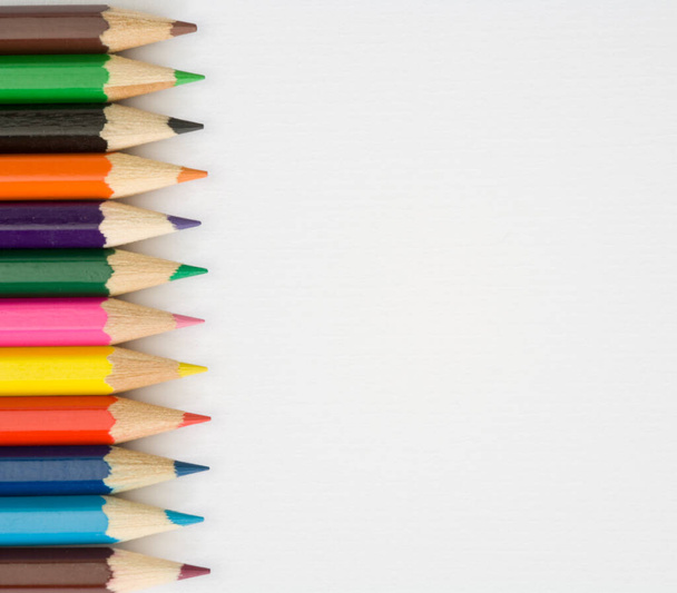 Kleurpotloden voor kinderen op een effen witte getextureerde papieren ondergrond - Foto, afbeelding