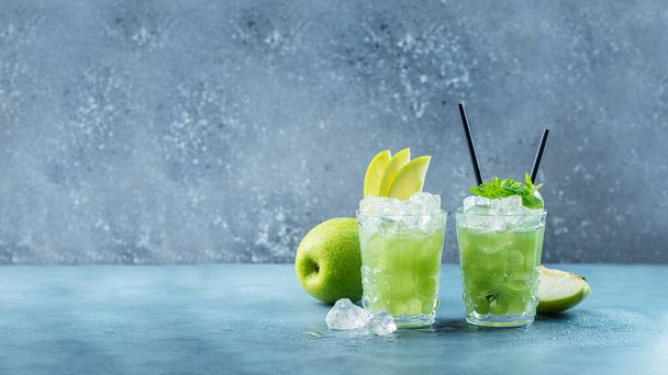 Green cocktail with ice and mint. Bar concept. Apple mojito with mint and ice on the blue background, selective focus image and slider format - Foto, Bild
