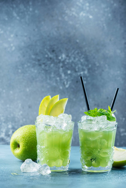 Green cocktail with ice and mint. Bar concept. Apple mojito with mint and ice on the blue background, selective focus image - Zdjęcie, obraz