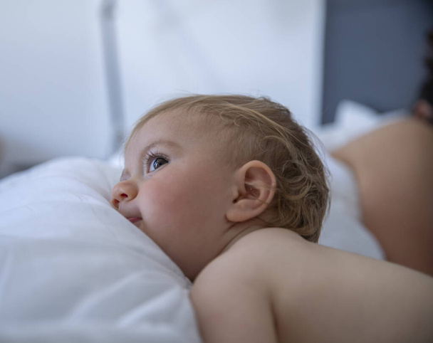 cute baby girl with blond hair on a bed with her mum - Φωτογραφία, εικόνα