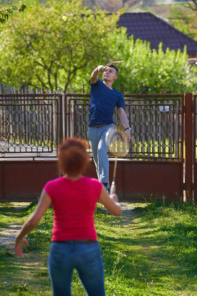 Madre e hijo jugando bádminton en el patio junto a la casa
 - Foto, imagen