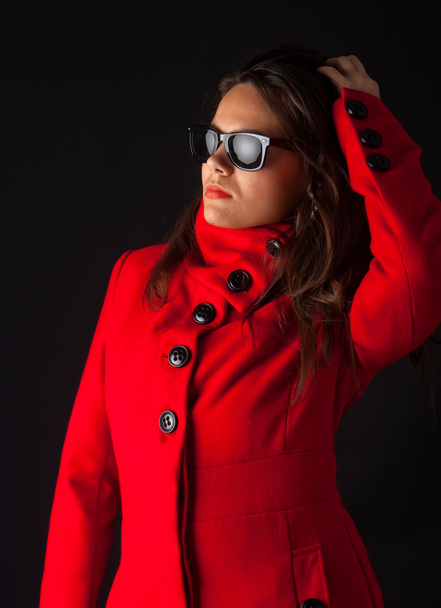 Attractive sexy brunette wearing sunglasses and winter coat, isolated on black background - Fotoğraf, Görsel