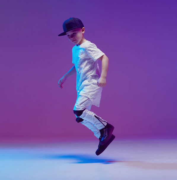 Cool young boy child dancing hip hop in the Studio against the background of neon lights. Break dance poster. - Foto, Imagen