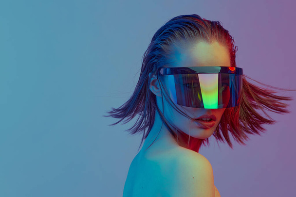 Cool stylish girl with a fashionable hairstyle and stylish glasses with a large glass poses on a bright neon background. - 写真・画像