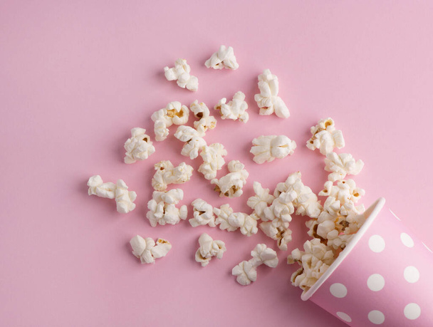 Palomitas de maíz derramadas sobre un fondo rosa, cine, películas y concepto de entretenimiento
 - Foto, imagen