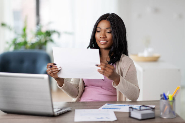 счастливая женщина с ноутбуком и бумагами в домашнем офисе
 - Фото, изображение