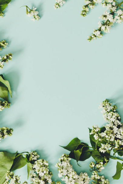 Voorjaarsbloemen. Frame van twijgen van bloeiende witte lila op een blauwe achtergrond. Bovenaanzicht. plaats voor tekst / - Foto, afbeelding
