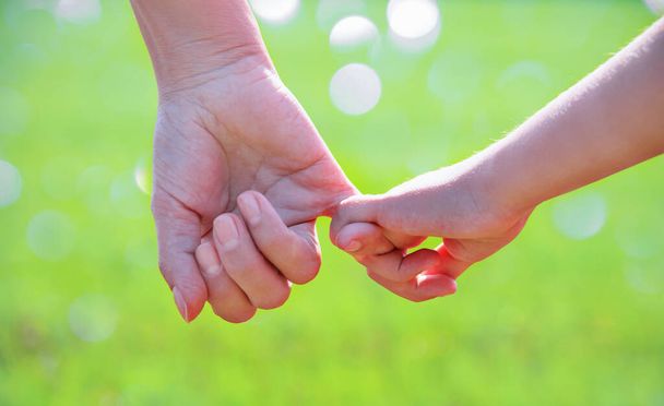 een ouder houdt de hand van een klein kind vast - Foto, afbeelding