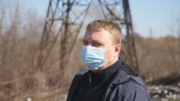 Portret van een man met medisch gezichtsmasker staat op straat tijdens de COVID-19 epidemie. Een man met een beschermend masker van het virus buiten. Concept van gezondheid en veiligheid van coronaviruspandemie - Video