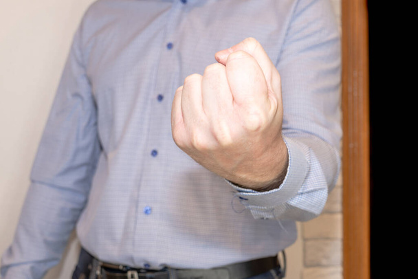 Раздражённый мужчина в квартире показывает сжатый кулак
. - Фото, изображение