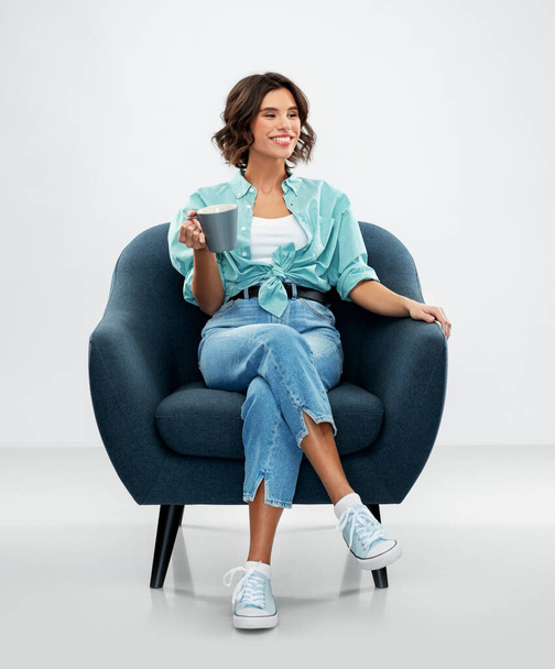 woman sitting in chair with cup of coffee or tea - Фото, зображення