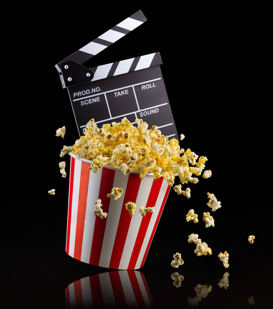 Flying popcorn and film clapper board isolated on black background - Foto, Bild