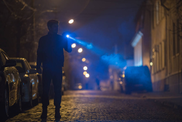 懐中電灯を持った男が道路に立っている。夜の時間 - 写真・画像