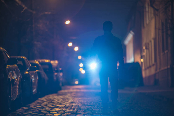 De man met een zaklamp inspecteert de straat. Avond nacht - Foto, afbeelding