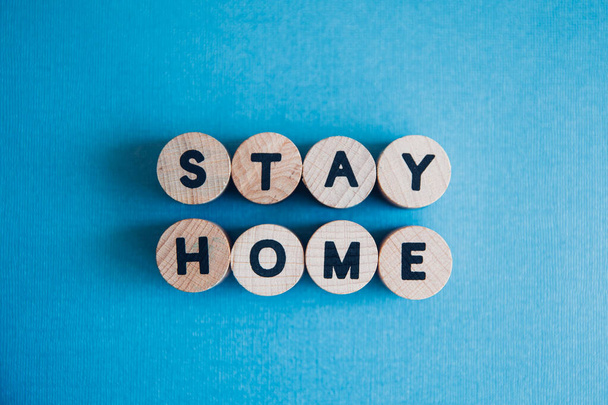 Blue background with Stay Home text written from wooden letters. Quarantine themed image during pandemics outbreak.  - Фото, зображення