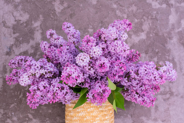 Beautiful bouquet of purple lilac in a vase on a background of a gray wall.Close-up. - Photo, Image